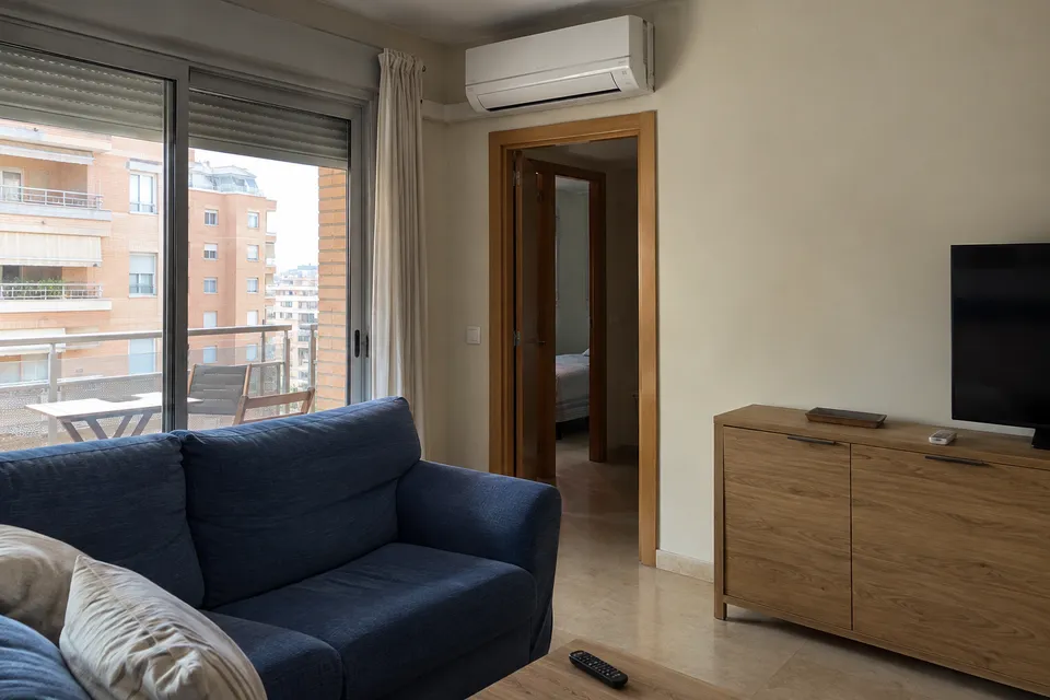 Aire acondicionado split en un salón con balcón y sofá azul