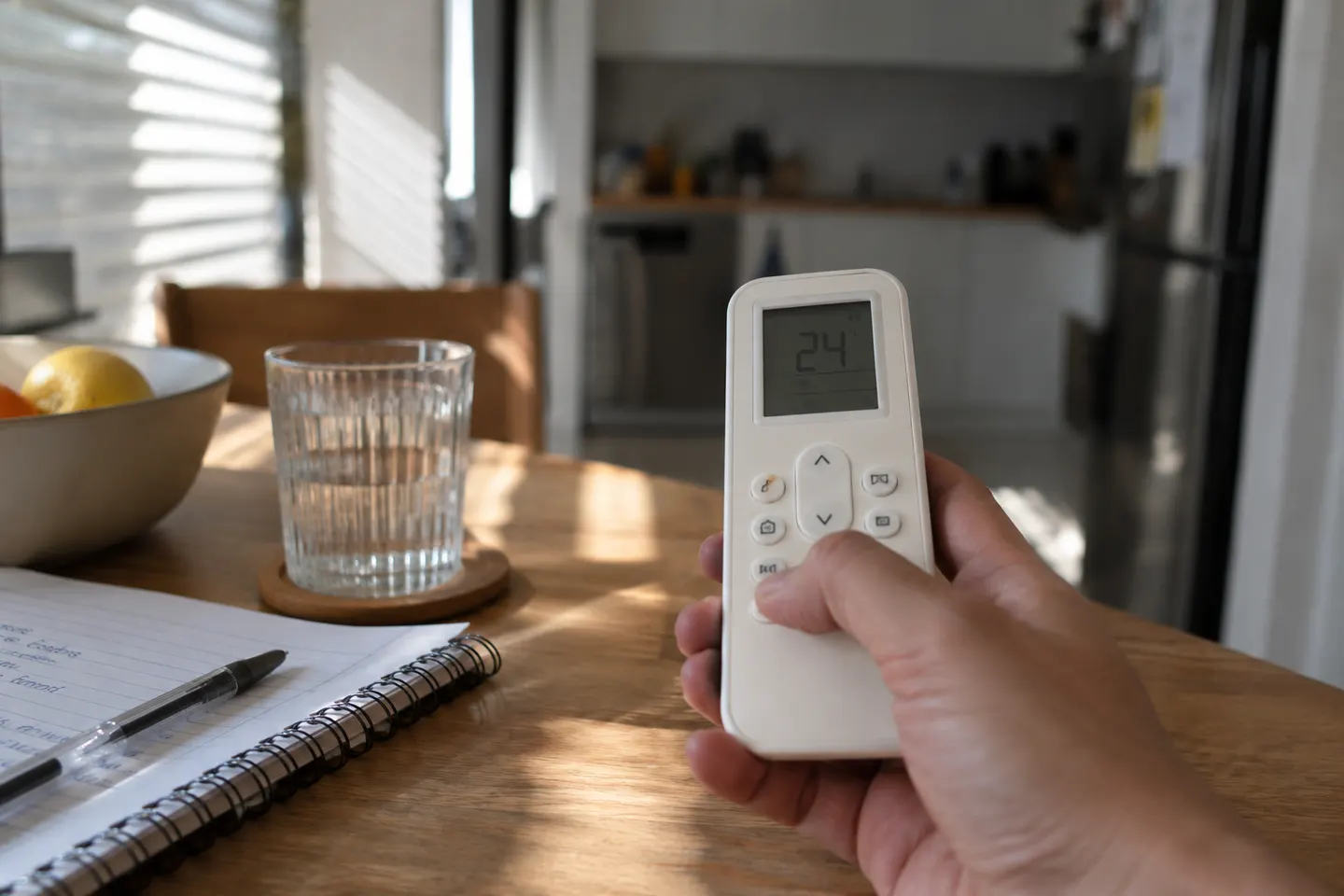 Mando de aire acondicionado junto a un cuaderno sobre una mesa doméstica