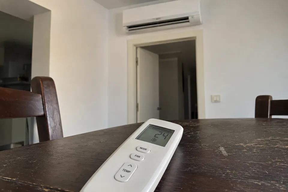 Mando de aire acondicionado con pantalla y botones de modo sobre una mesa