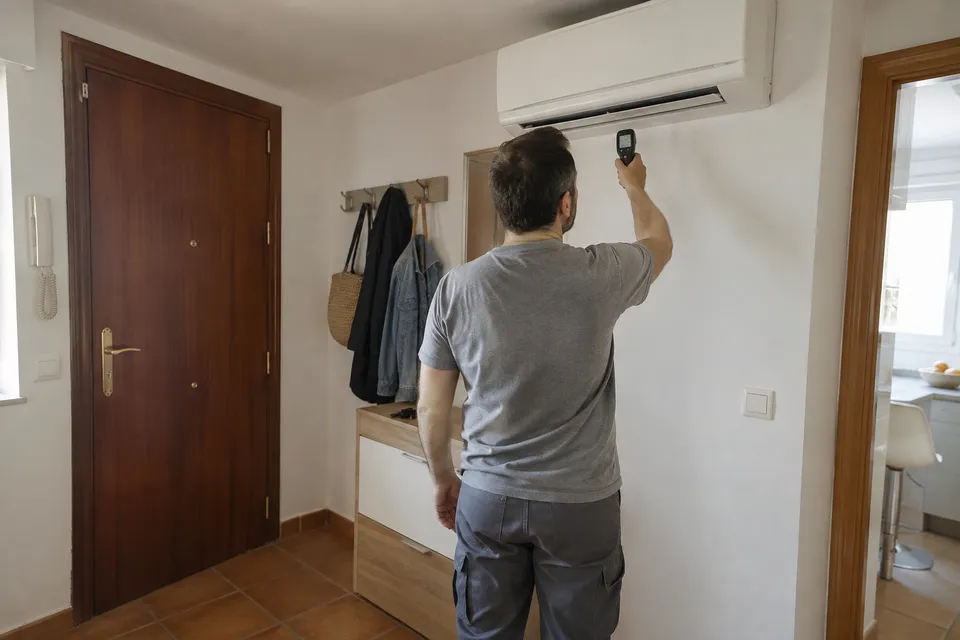 Revisión de un split con un termómetro de mano en la entrada de una vivienda